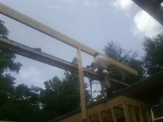 Carpenter setting a ridge beam over a new addition frame — Ice Dam Removal by Roofing Brothers in Bayville