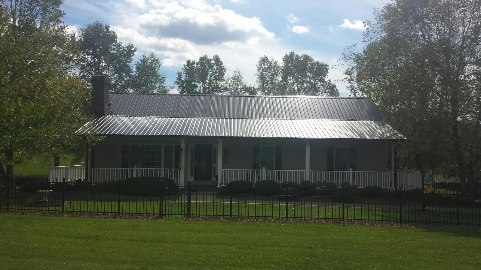 Gray metal roof on a brick ranch with a full width front porch — Gutter Guard Installation work by our crew in Bayville